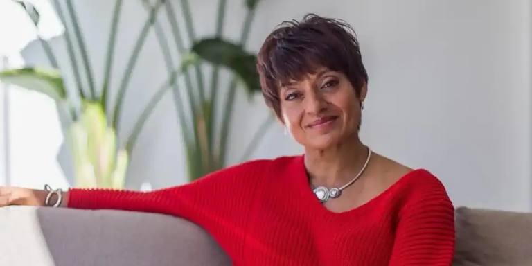 Dr Nerina Ramlakhan, sleep physiologist, smiling while seated on a sofa.