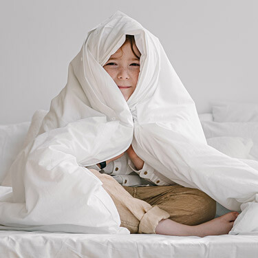 Boy sitting under a duvet